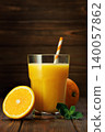Glass of freshly squeezed orange juice with striped straw, mint and citrus fruits on rustic wooden table 140057862