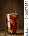 Cola with numerous ice cubes and effervescent bubbles, condensation forming on the glass, providing cool and refreshing drink experience 140057864