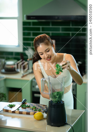 Woman adding fresh kale into blender for healthy smoothie 140058560