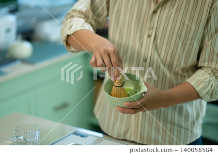 Close up of man whisking matcha tea with bamboo chasen in home kitchen 140058584