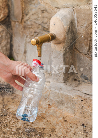 Hand filling plastic bottle with drinking water from public stone fountain Hand filling plastic bottle with drinking water from public stone fountain 140058643