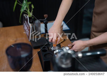 Young barista making coffee, coffee preparation service concept. 140058647