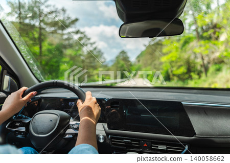 Woman driving car on scenic countryside road viewed from front passenger seat Woman driving car on scenic countryside road viewed from front passenger seat 140058662