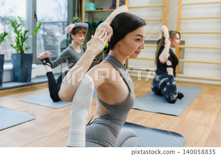 Women practicing king pigeon yoga pose in studio Women practicing king pigeon yoga pose in studio 140058835