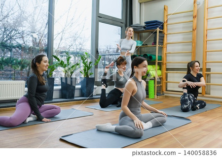 Group yoga class with instructor guiding women in studio 140058836