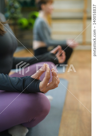 Women practicing meditation during yoga class indoors Women practicing meditation during yoga class indoors 140058837