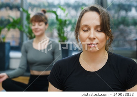 Women meditating together during indoor yoga session Women meditating together during indoor yoga session 140058838