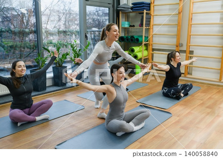 Yoga instructor helping woman stretch during class Yoga instructor helping woman stretch during class 140058840