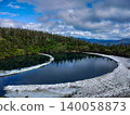 Summer at Kagamiike Pond in Hachimantai: The primeval forest is perfectly reflected on the deep blue surface of the water, creating a mirror-like surface and a crescent moon with lingering snow. 140058873