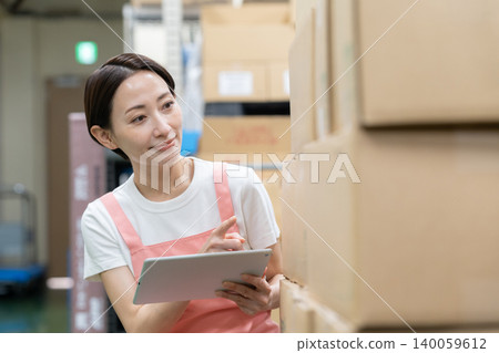 Middle-aged female worker in a warehouse Middle-aged female worker in a warehouse 140059612