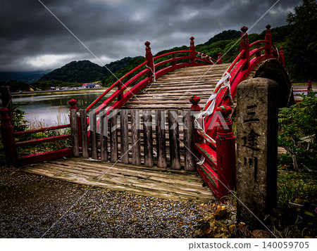 Mount Osorezan in Aomori, one of Japan's three most sacred sites: A dark photograph of the arched bridge reminiscent of a protective barrier and the heavy, overcast clouds. Mount Osorezan in Aomori, one of Japan's three most sacred sites: A dark photograph of the arched bridge reminiscent of a protective barrier and the heavy, overcast clouds. 140059705