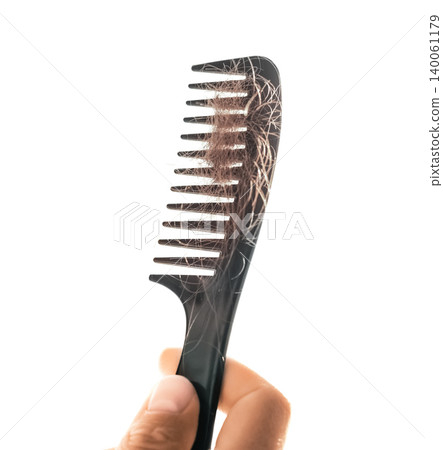 Hand holding a black plastic comb with a lot of tangled shed hair, isolated on a white background. Concept of hair loss, alopecia, and hair care problems. 140061179
