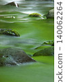 The still water surface reflects the fresh green leaves. 140062264