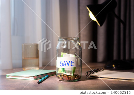 Close up of transparent money jar. Represents traditional saving methods and conscious money management for future security Close up of transparent money jar. Represents traditional saving methods and conscious money management for future security 140062515