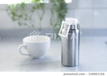 A tumbler with a heat retention function that holds a coffee drip pack; the image is of brewing piping hot coffee. 140063188