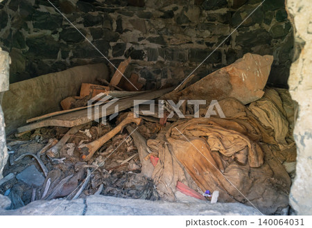 Interior view of an ancient Dargavs burial crypt, revealing human skeletal remains and deteriorated textiles Interior view of an ancient Dargavs burial crypt, revealing human skeletal remains and deteriorated textiles 140064031