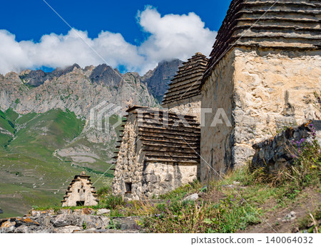Ancient stone crypts on a green mountain slope in the City of the Dead Dargavs, Russia 140064032