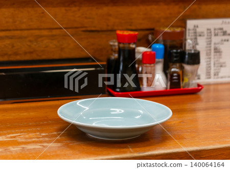 一隻淺藍色的空盤子放在當地一家中餐館的櫃檯上。 一隻淺藍色的空盤子放在當地一家中餐館的櫃檯上。 140064164