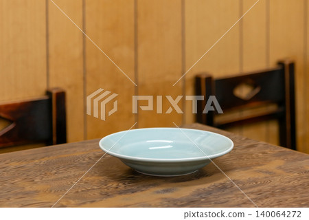 A light blue empty plate placed on a table in a local Chinese restaurant. 140064272