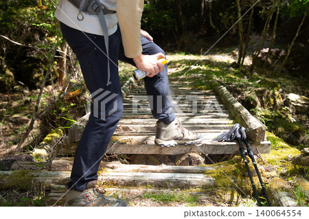 A Japanese man sprays insect repellent on his trekking shoes and trousers. A Japanese man sprays insect repellent on his trekking shoes and trousers. 140064554