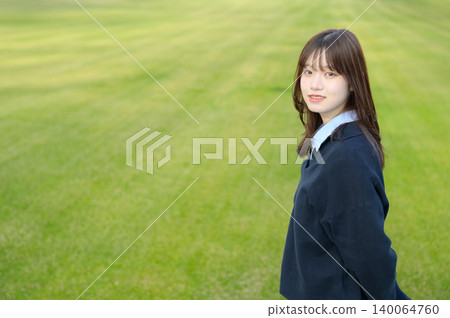 一名日本高中女生轉身,在草地上微笑。 一名日本高中女生轉身,在草地上微笑。 140064760