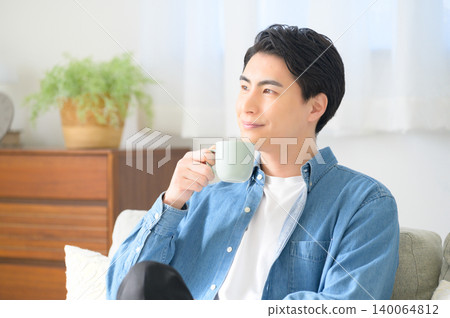 A Japanese man relaxing while drinking coffee. 140064812