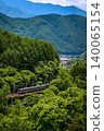 A 211 series train runs along the JR Chuo Main Line amidst the fresh greenery. 140065154