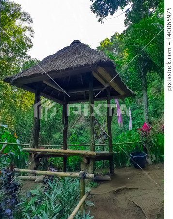 Traditional wooden gazebo with thatched roof in tropical jungle garden surrounded by lush green vegetation, Bali, Indonesia Traditional wooden gazebo with thatched roof in tropical jungle garden surrounded by lush green vegetation, Bali, Indonesia 140065975