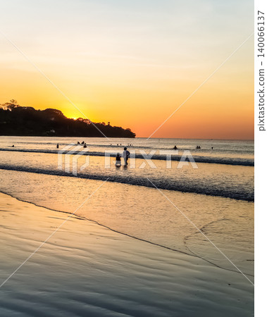 People Silhouetted on Tropical Beach at Golden Sunset with Sun Reflection on Wet Sand People Silhouetted on Tropical Beach at Golden Sunset with Sun Reflection on Wet Sand 140066137