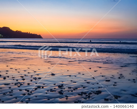 Jimbaran Beach shoreline at twilight with orange afterglow sky and silhouetted headland, Bali, Indonesia Jimbaran Beach shoreline at twilight with orange afterglow sky and silhouetted headland, Bali, Indonesia 140066140