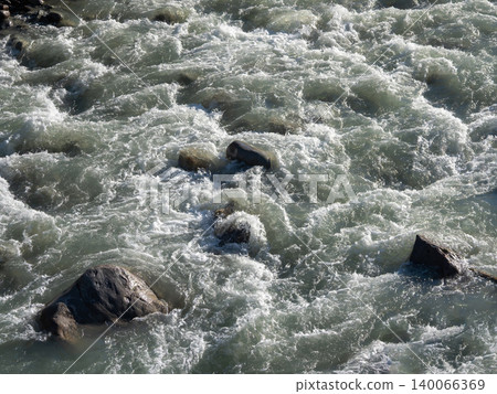 Rushing water crashes over jagged rocks Rushing water crashes over jagged rocks 140066369