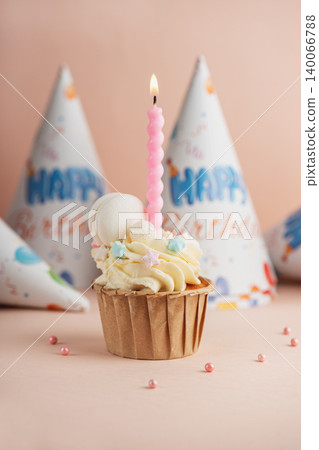 Birthday cupcake with lit candle and party hats Birthday cupcake with lit candle and party hats 140066788