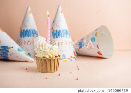 Birthday cupcake with lit candle and party hats Birthday cupcake with lit candle and party hats 140066789