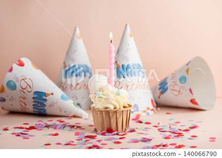 Birthday cupcake with lit candle and party hats Birthday cupcake with lit candle and party hats 140066790
