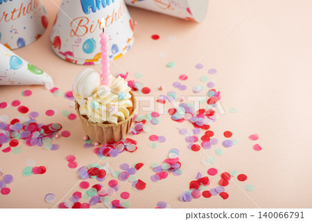 Birthday cupcake with lit candle and party hats Birthday cupcake with lit candle and party hats 140066791