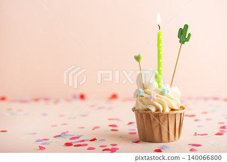 Frosted birthday cupcake with burning candle and confetti Frosted birthday cupcake with burning candle and confetti 140066800