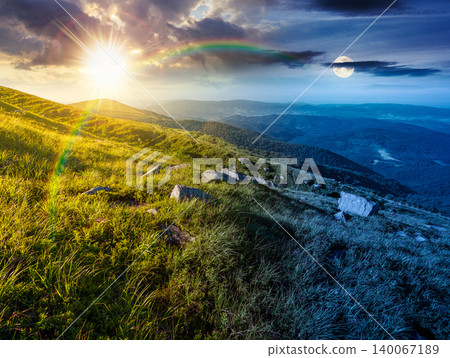 mountain landscape with grass and rock on a slope. day meet night. view in to the distant valley of carpathian mountains. sun and moon in harmony over mountainous scenery of ukraine on summer solstice mountain landscape with grass and rock on a slope. day meet night. view in to the distant valley of carpathian mountains. sun and moon in harmony over mountainous scenery of ukraine on summer solstice 140067189
