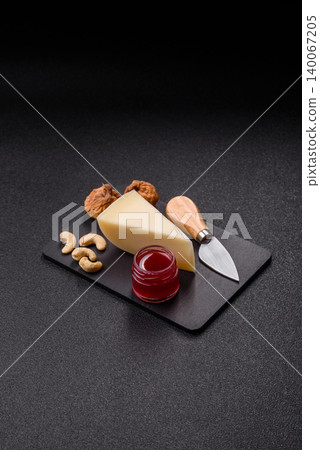 Aged cheese in a triangular block with jam, figs, and nuts. Aged cheese Aged cheese in a triangular block with jam, figs, and nuts. Aged cheese 140067205