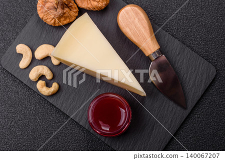Aged cheese in a triangular block with jam, figs, and nuts. Aged cheese Aged cheese in a triangular block with jam, figs, and nuts. Aged cheese 140067207