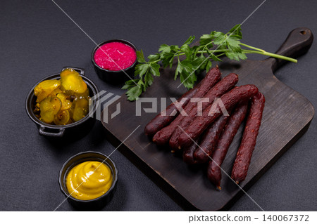 Smoked sausages on cutting board with various sauces Smoked sausages on cutting board with various sauces 140067372
