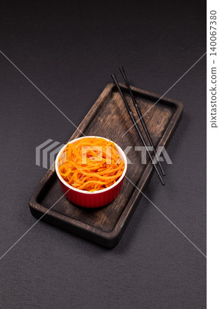 Korean carrot salad in a red bowl with chopsticks Korean carrot salad in a red bowl with chopsticks 140067380