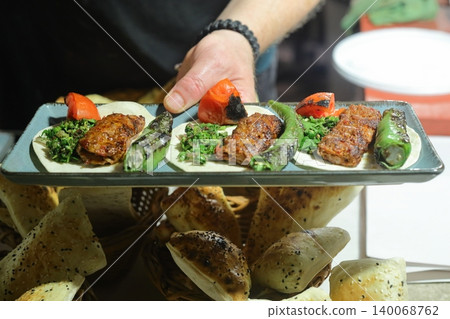 A plate with a shish and adana kebab in the hands of a cook closeup A plate with a shish and adana kebab in the hands of a cook closeup 140068762