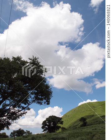 夏日的藍天上,大片白雲和綠山巒綿延展開。 夏日的藍天上,大片白雲和綠山巒綿延展開。 140068821