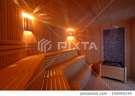 Seat in sauna room. Empty wooden steam room with stone heater.Sauna room for good health. 140069244