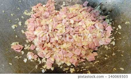 Sauteing Diced Ham and Chopped Onions in a Pan for Meal Preparation 140069303
