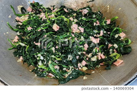Stir-fried spinach with diced ham and minced garlic in a rustic metal wok homemade healthy meal 140069304