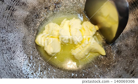 Yellow Butter Chunks Melting in a Hot Metal Pan for Home Cooking and Frying Yellow Butter Chunks Melting in a Hot Metal Pan for Home Cooking and Frying 140069306