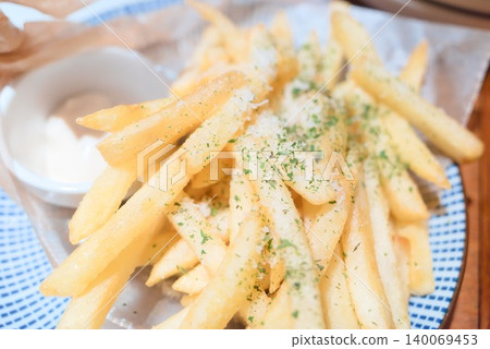 A plate of herb-flavored french fries served with a white sauce. 140069453