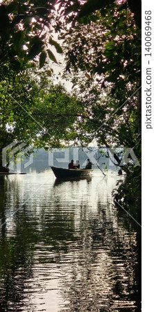People in a wooden boat on a quiet river, surrounded by a tropical forest. People in a wooden boat on a quiet river, surrounded by a tropical forest. 140069468