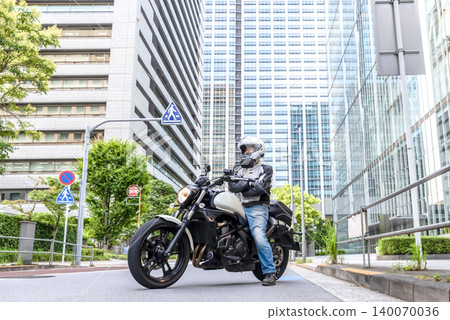 一名身材高大的摩托車騎士站在東京品川商業區。 140070036